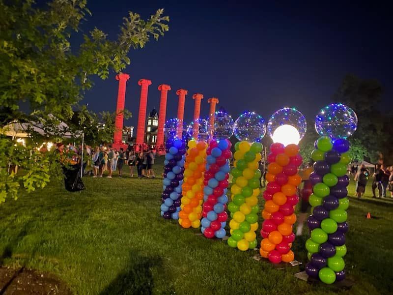 A row of colorful balloons are lined up in a park at night.