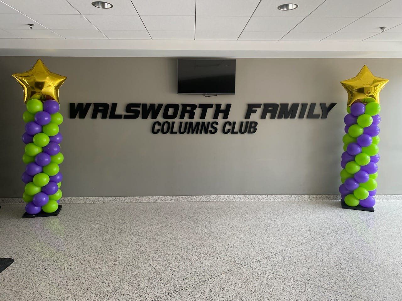 The walsworth family columns club is decorated with green and purple balloons