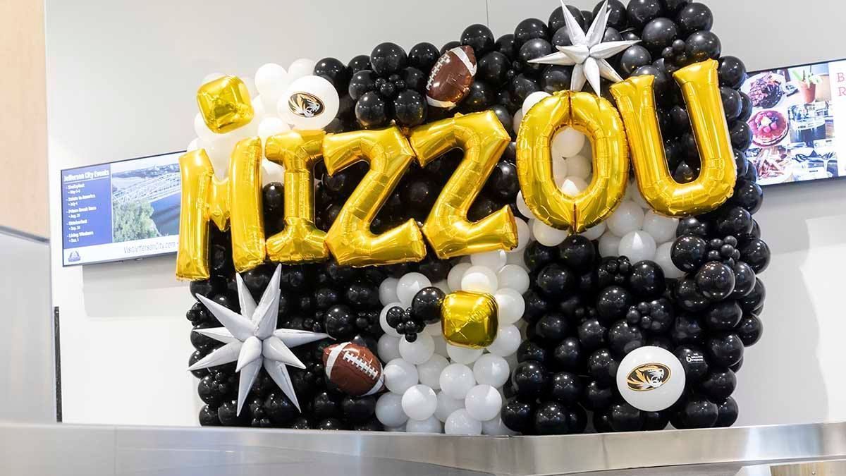 A wall made of balloons with the word mizzou on it.
