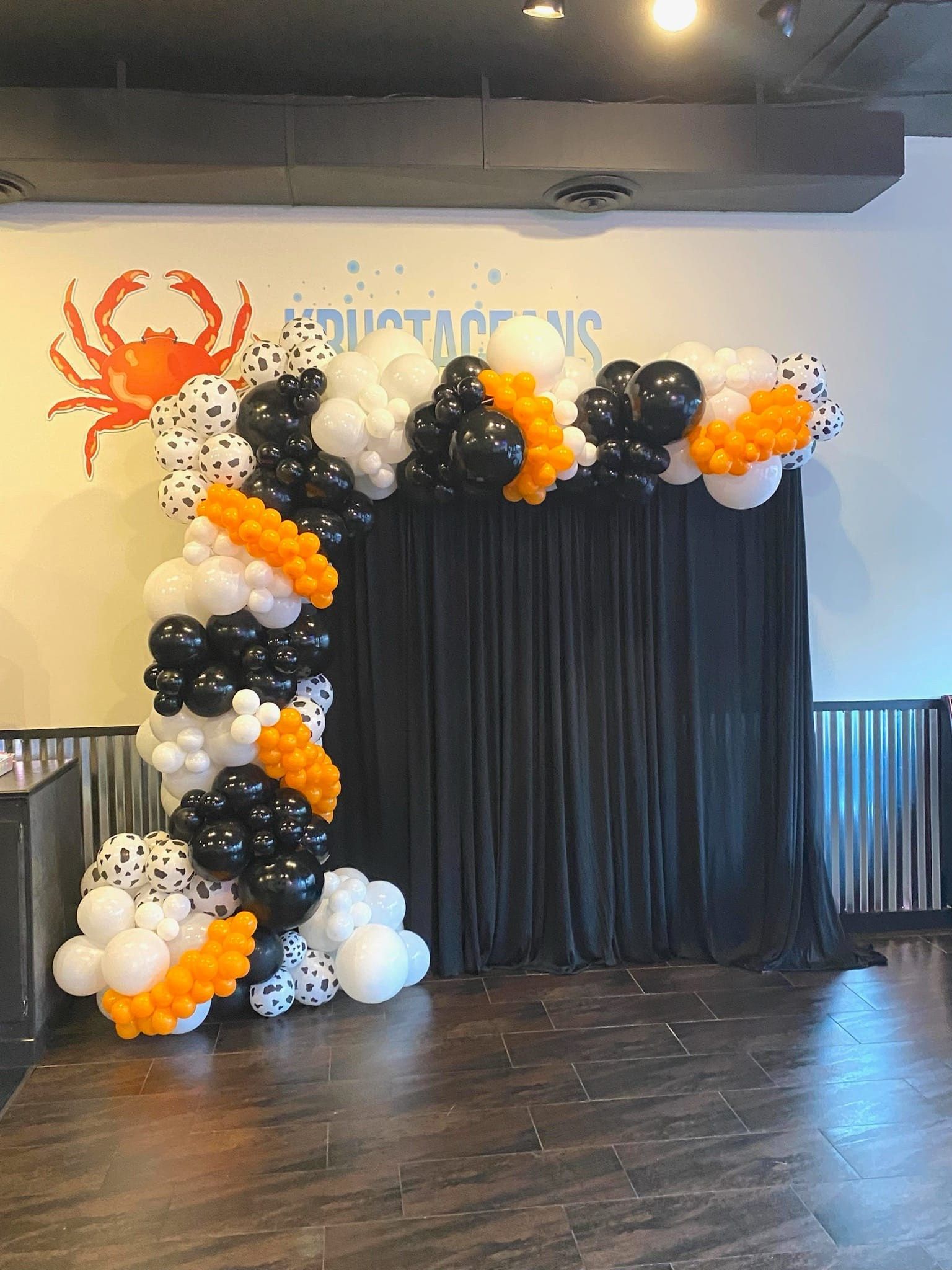 A room filled with balloons and a black curtain.