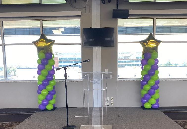 A podium with balloons and a microphone in a room.