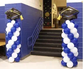 Two columns filled with blue and white balloons and graduation caps.
