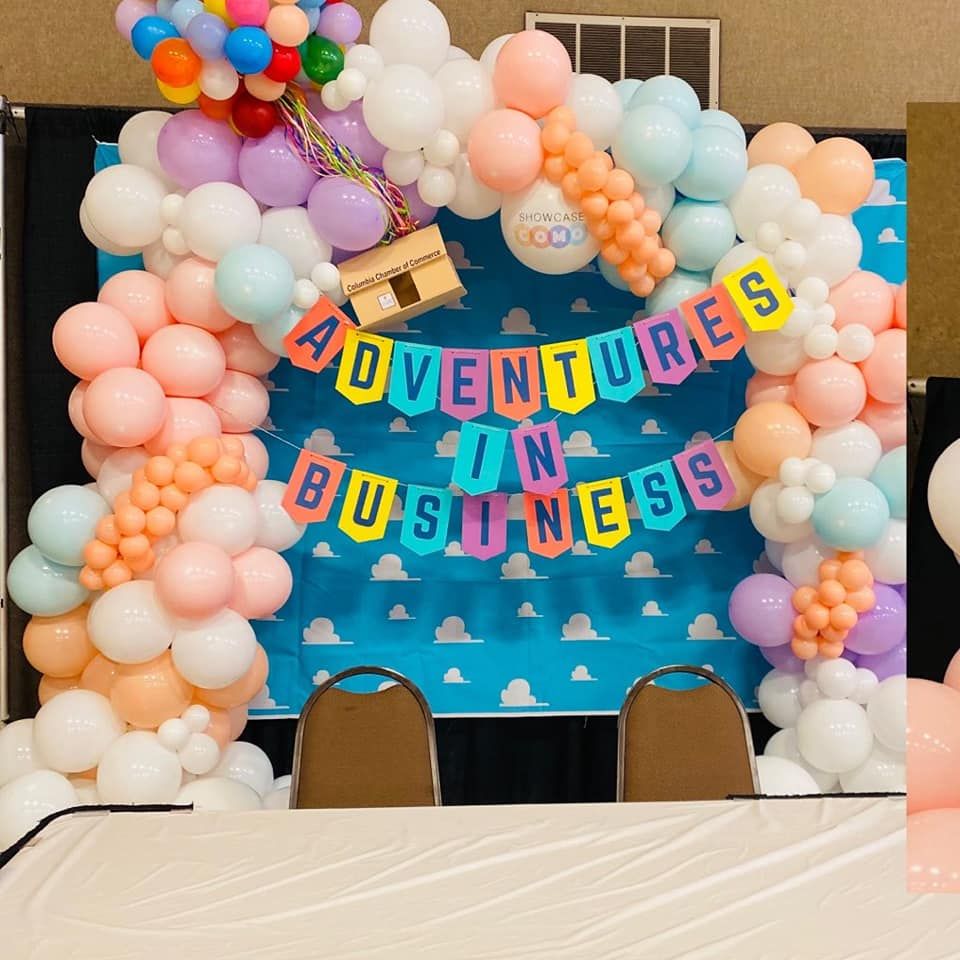 A banner that says adventures in business is surrounded by balloons