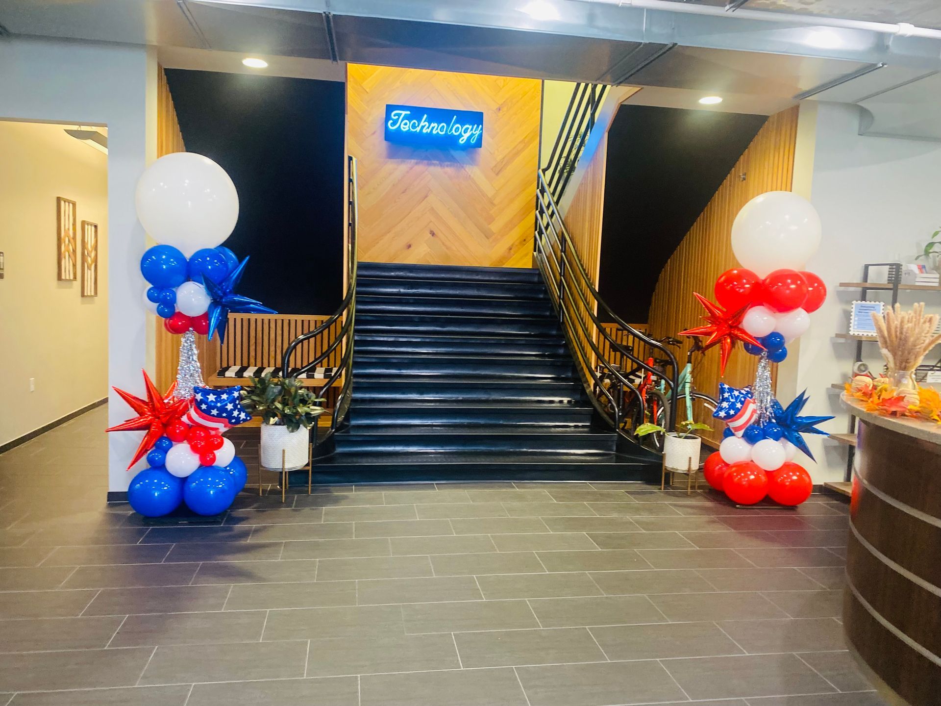 A lobby with red , white and blue balloons in front of a staircase.
