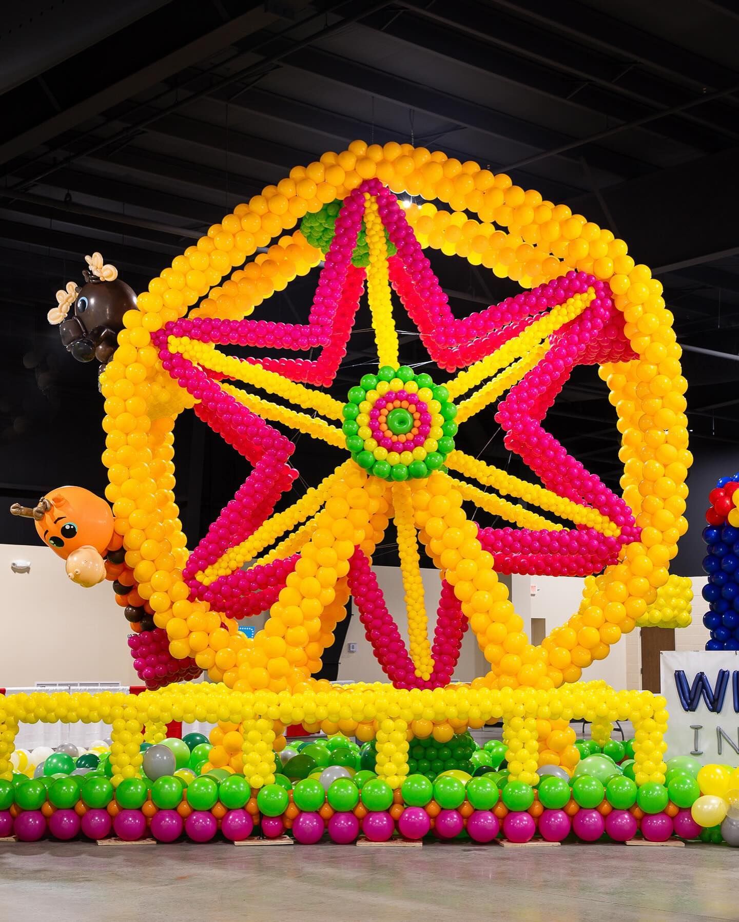 A ferris wheel made out of balloons with a giraffe on it