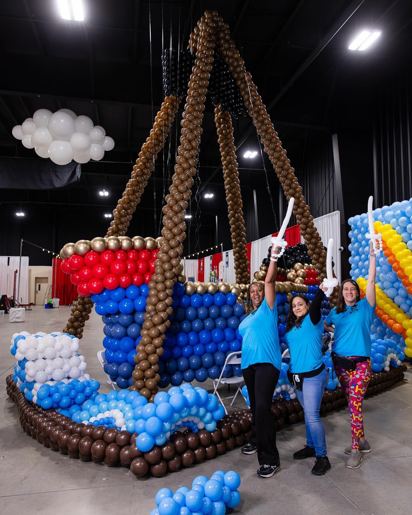 A group of people are standing in front of a boat made out of balloons.