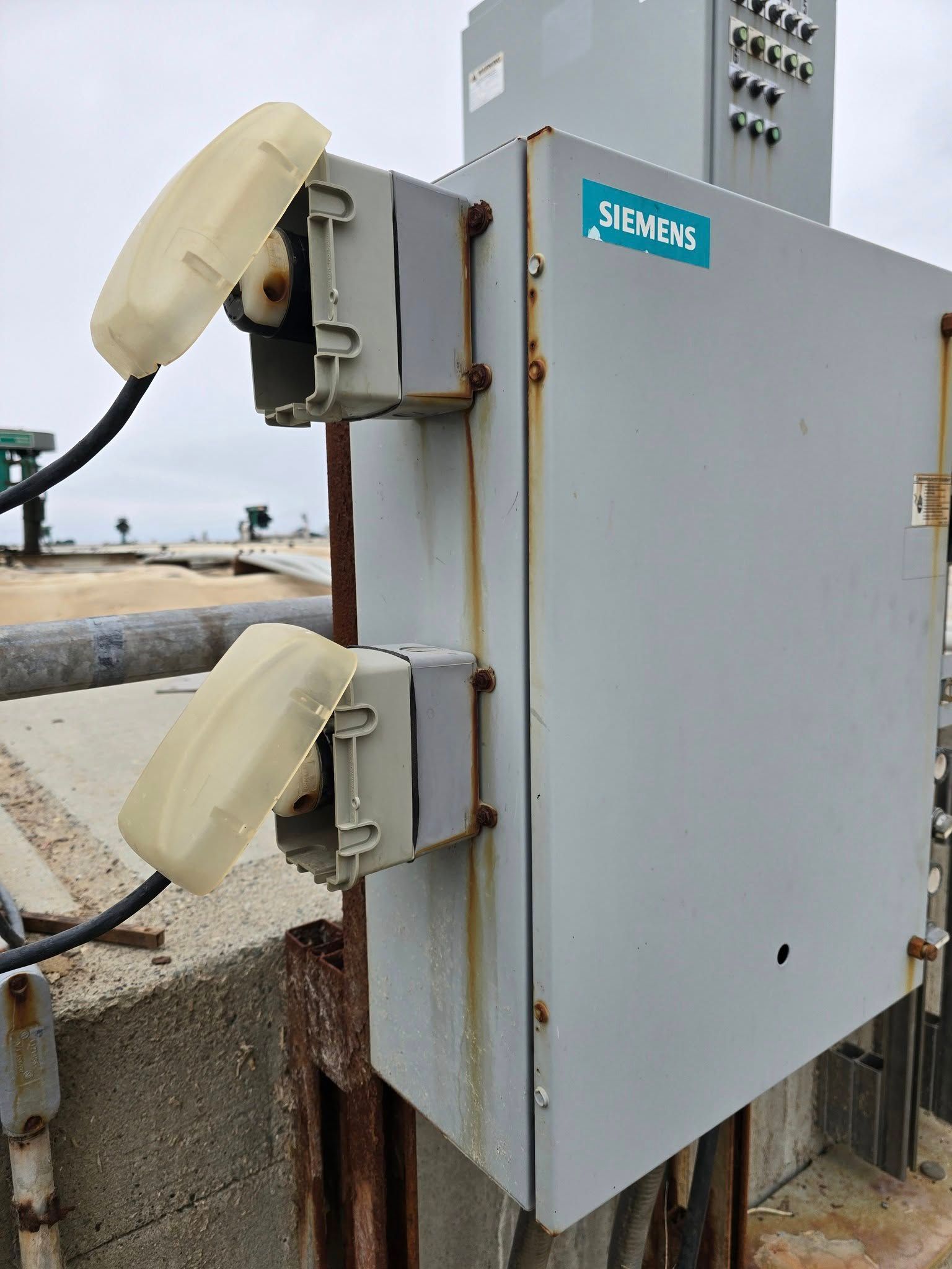 Outdoor electrical box with two open outlets and power cords.
