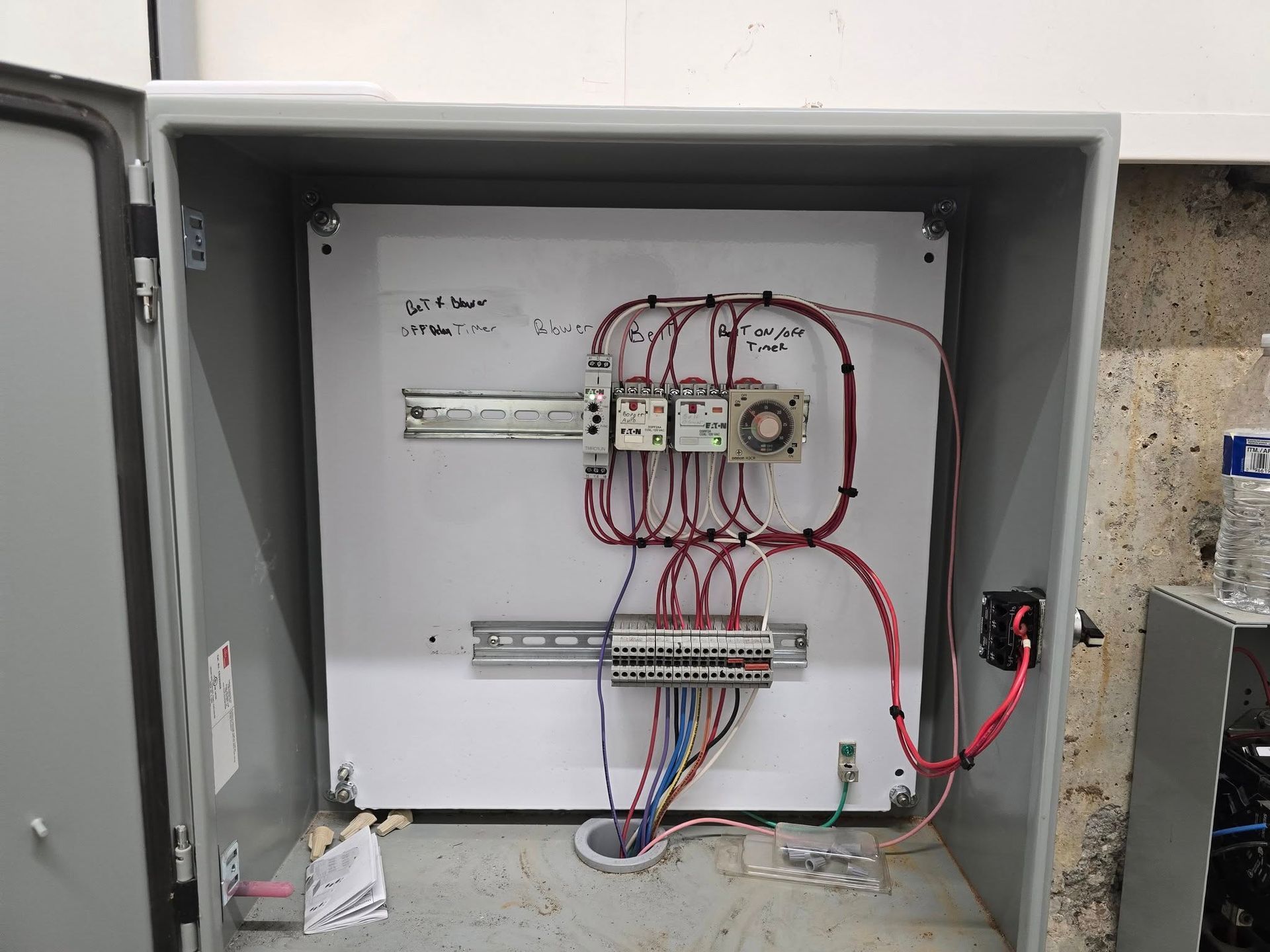 Electrical panel with wires and components inside a gray metal box.