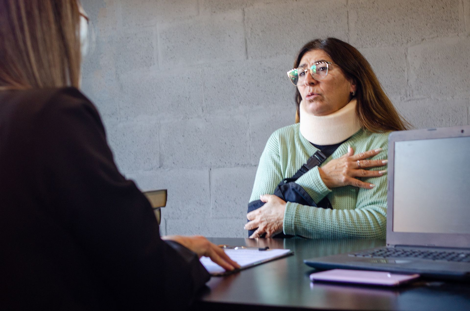 Injured woman in neck brace and arm sling consulting a personal injury attorney. Injured woman in neck brace and arm sling consulting a personal injury attorney.