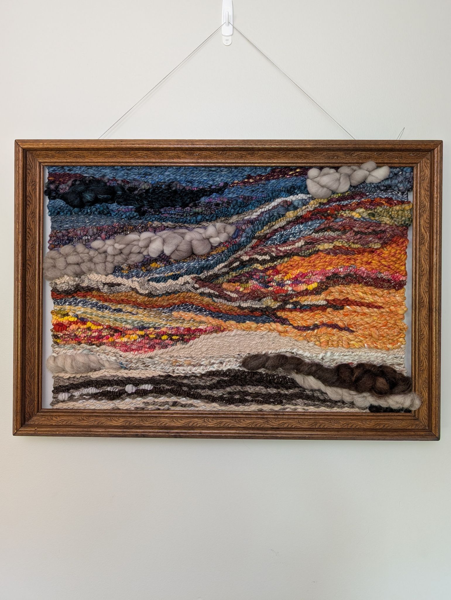 woven tapestry with blues and oranges in a frame