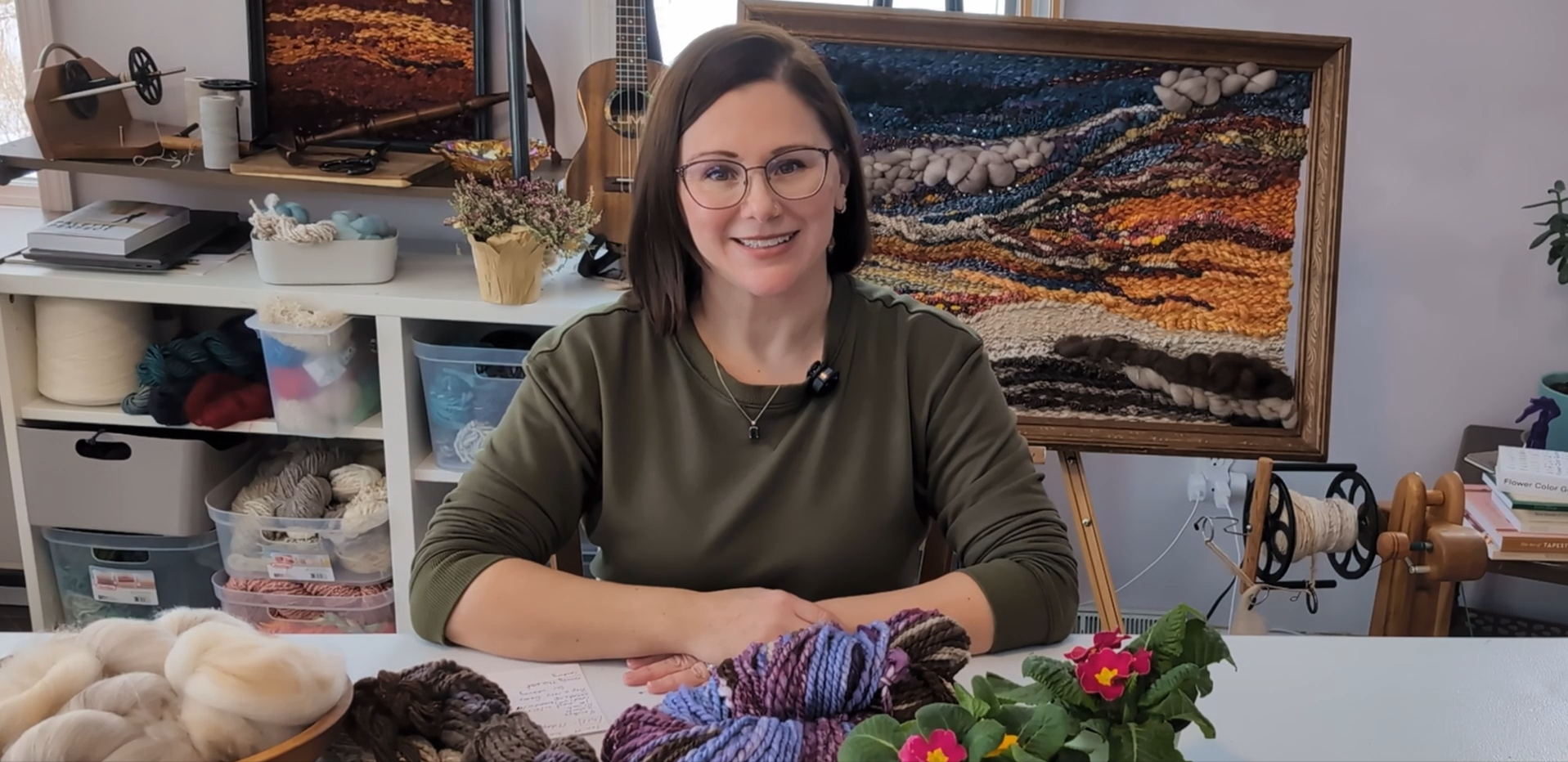 Woman holding a framed woven tapestry.
