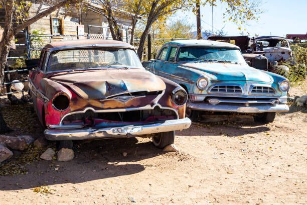 Two vintage, rusted cars parked outdoors: one red, one blue.