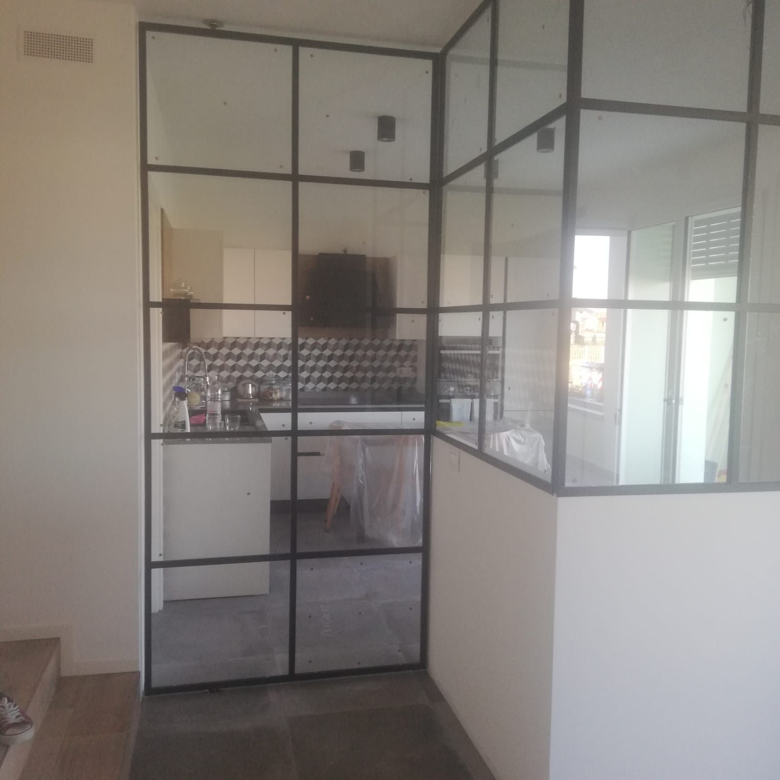 una cucina con un muro di vetro che separa il soggiorno e la cucina