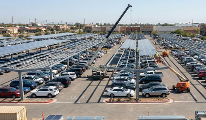 התקנת פאנלים סולאריים מעל מגרש חניה, בנוכחות עגורן ועובדים.