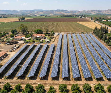 מערך פאנלים סולאריים בשדה עם אדמות חקלאיות מסביב ונוף כפרי מרוחק.