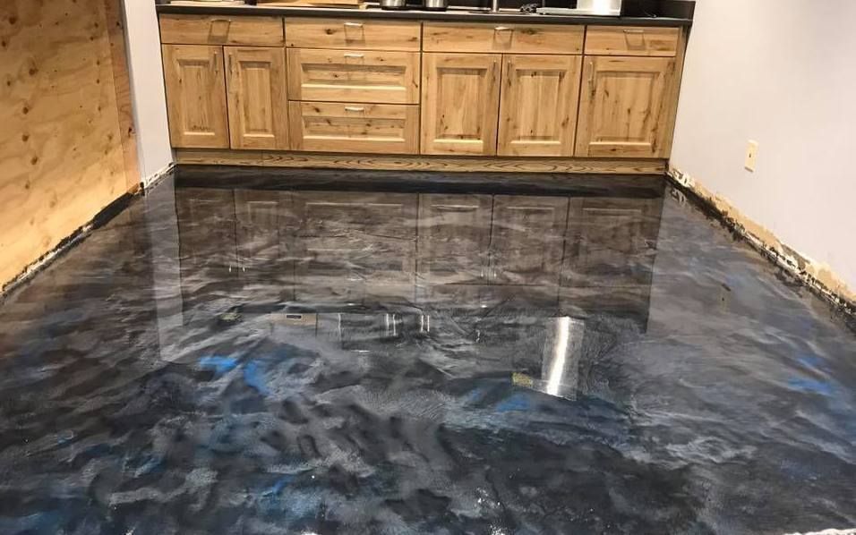 A man is painting a concrete floor with a roller.