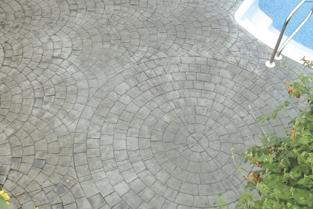 A circular brick walkway next to a swimming pool