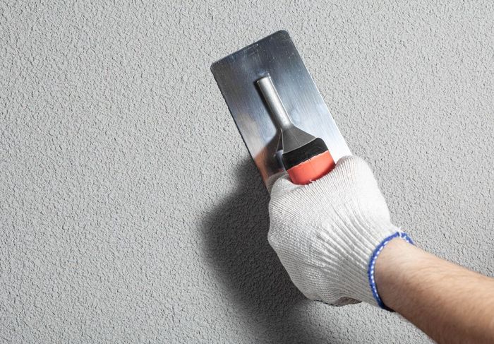 A person is using a trowel to plaster a wall.