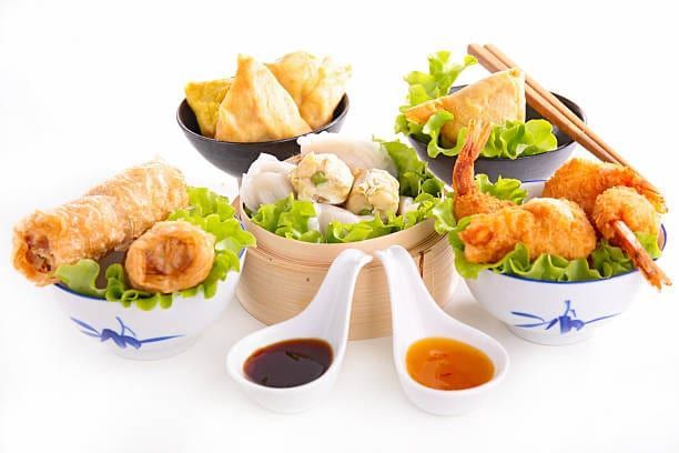 Assortment of Chinese appetizers in small bowls, with dipping sauces.