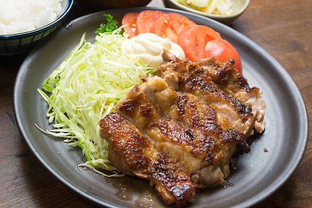 Grilled chicken with sliced tomatoes, shredded cabbage, and mayonnaise on a plate.