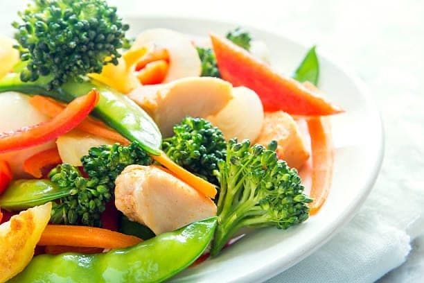 A plate of colorful stir-fry with broccoli, carrots, and mushrooms.
