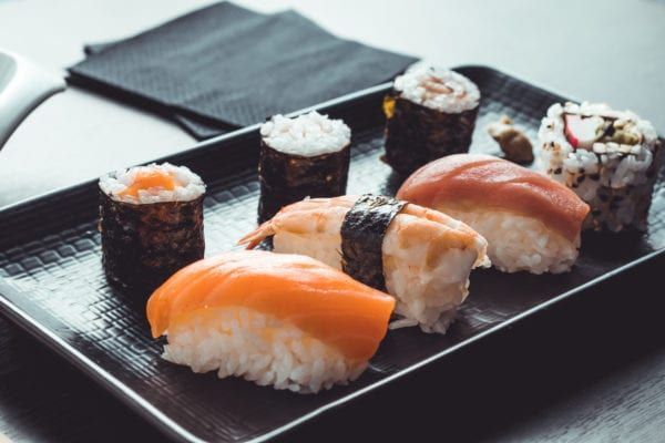 Sushi platter with various rolls and nigiri, salmon and shrimp prominent.
