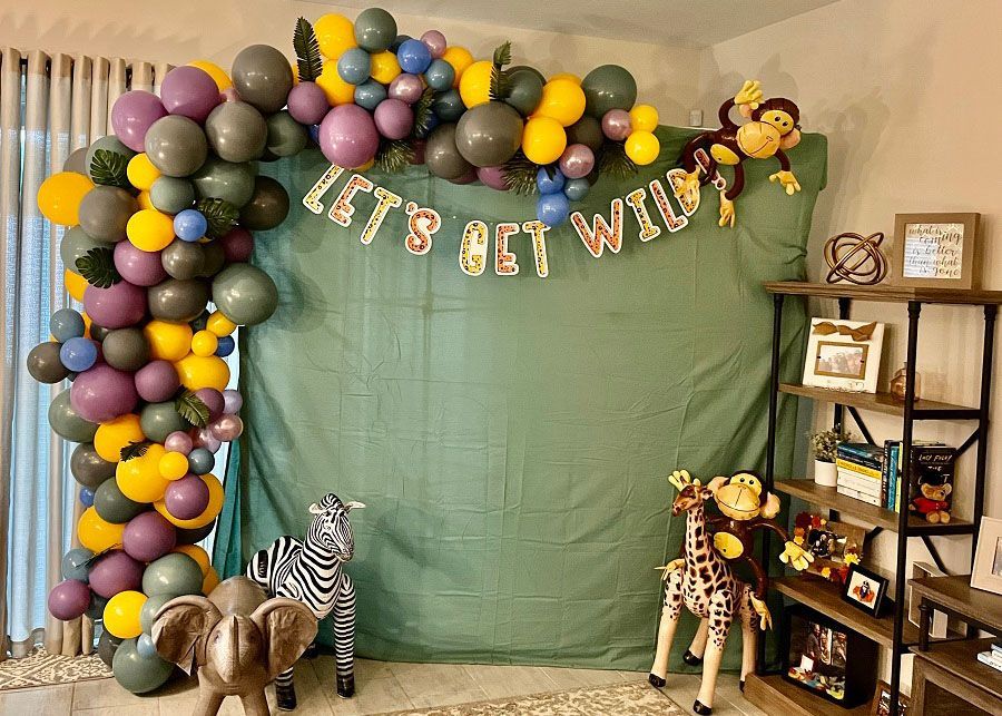 A room decorated with balloons and animals for a baby shower.