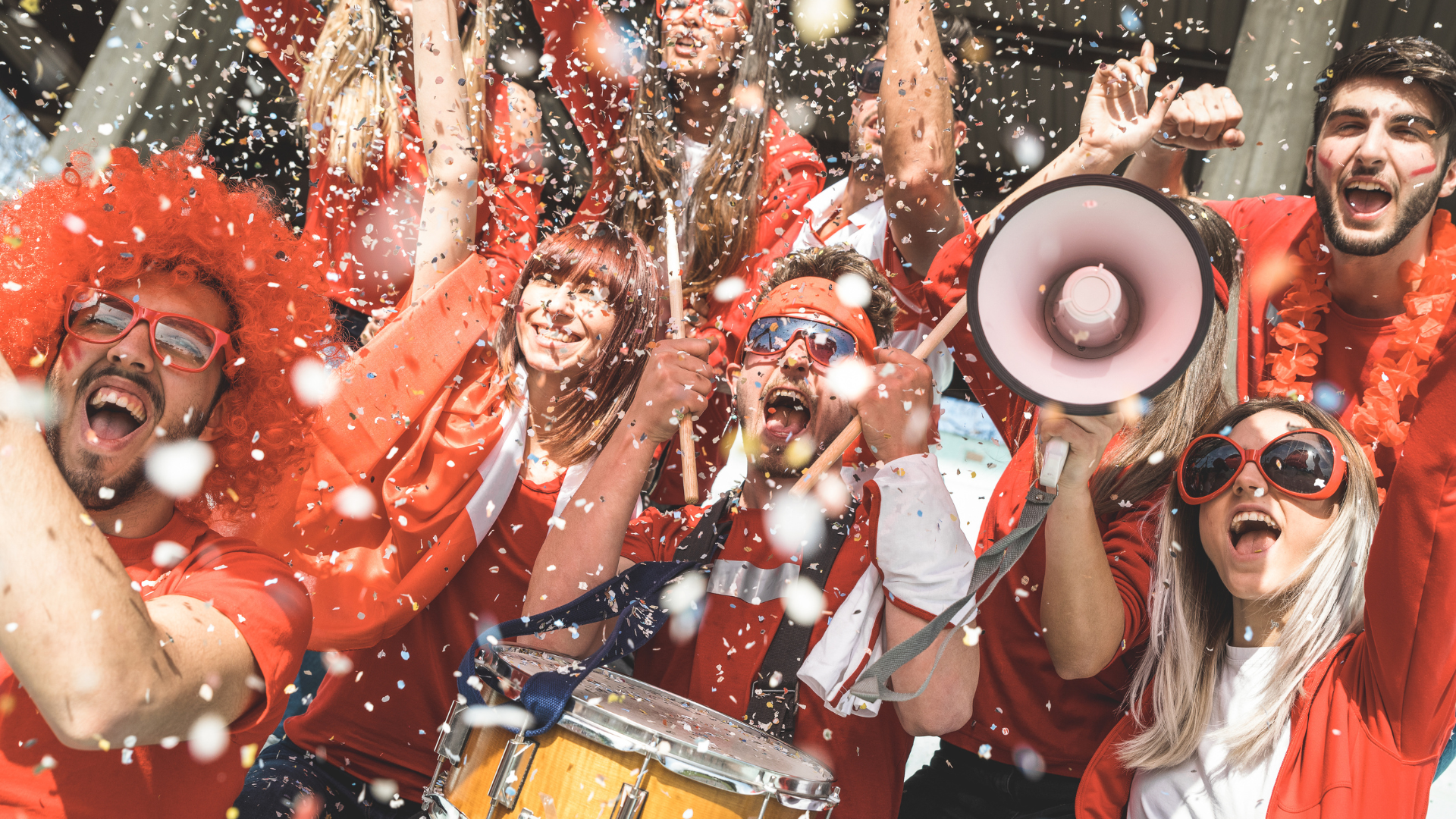 A group of people in red shirts are holding a megaphone and a drum.