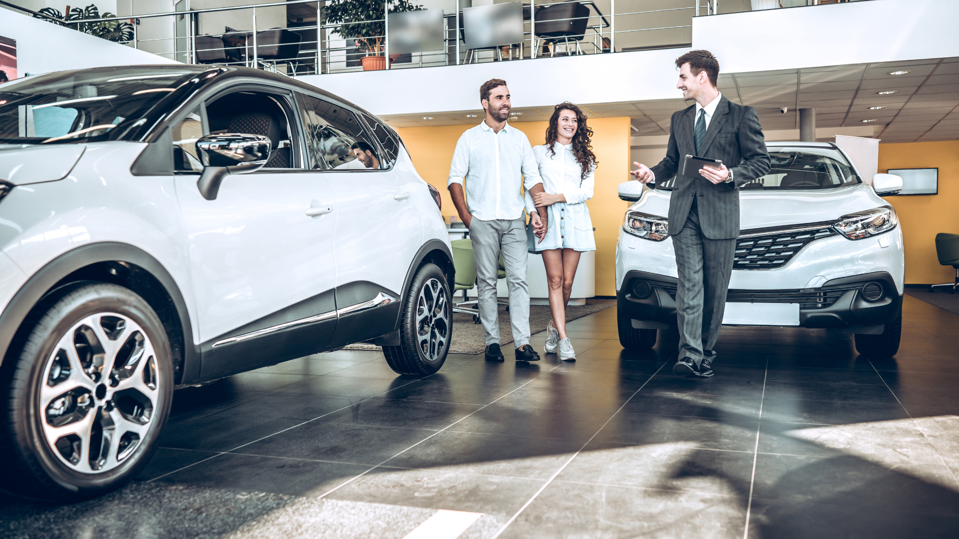 A man and a woman are looking at a car in a showroom.