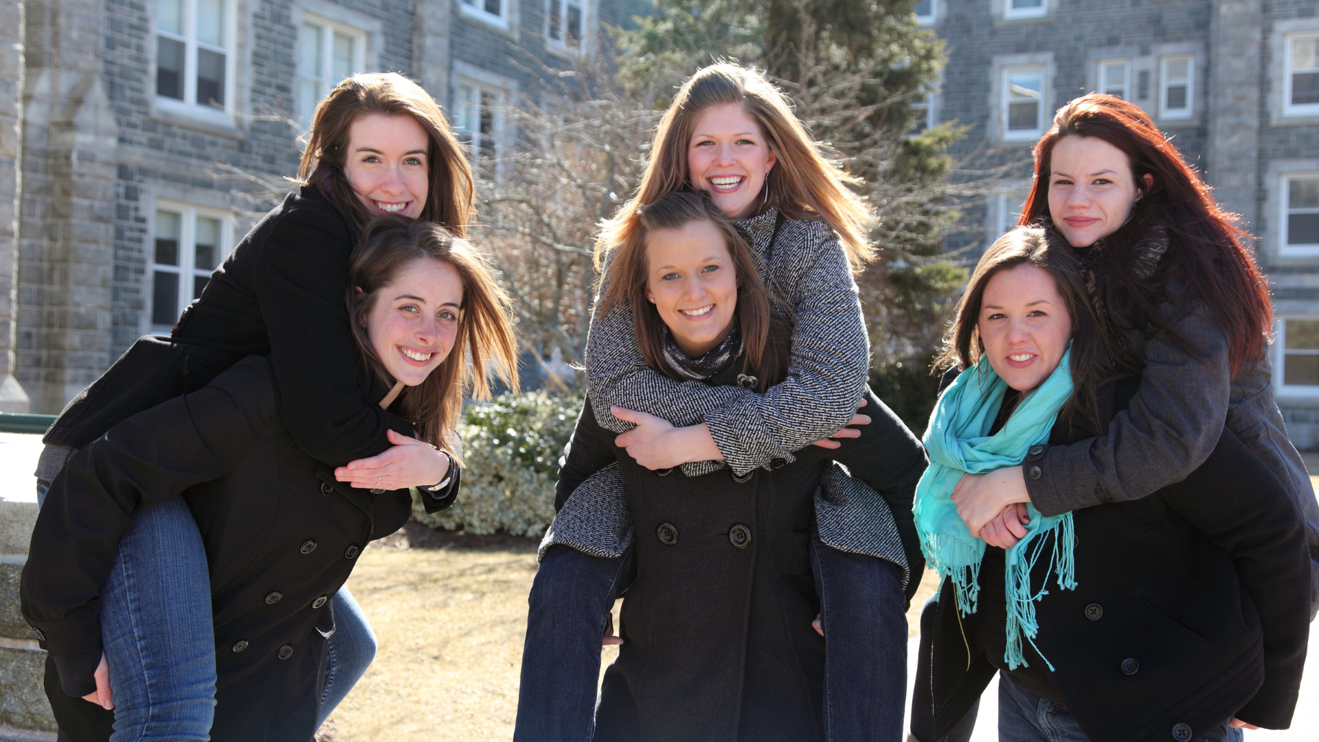 A group of young women are posing for a picture in front of a building