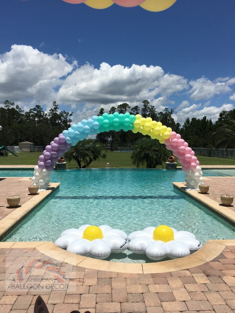 A pool decorated with balloons and a rainbow arch