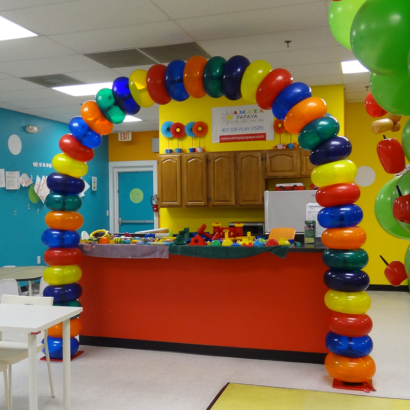 A colorful balloon arch in a room with a sign that says ' a ' on it