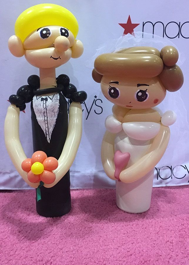 A bride and groom made out of balloons are standing next to each other