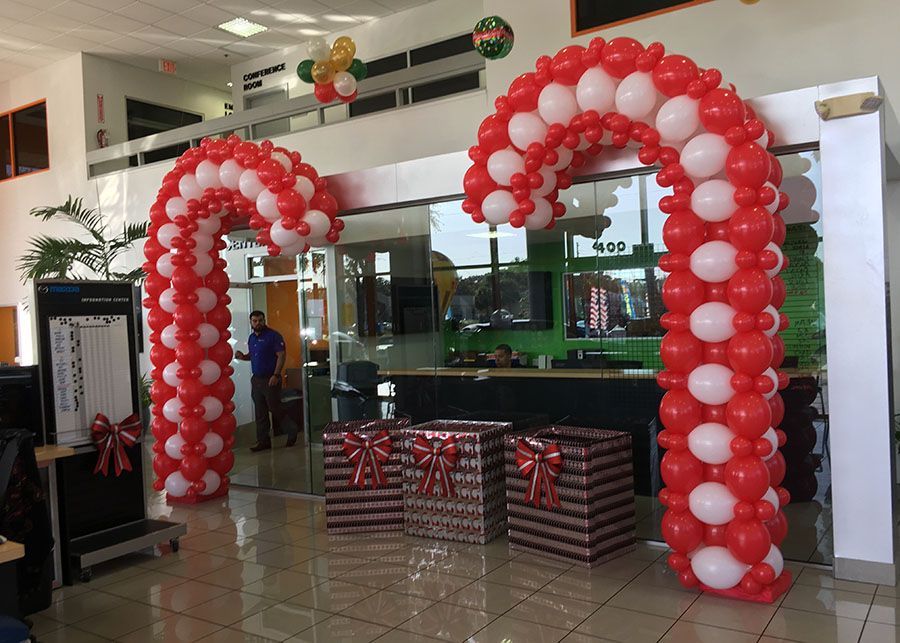 A candy cane made out of red and white balloons in a room.