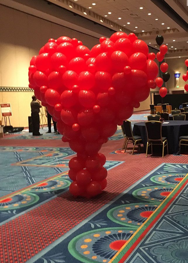 A large heart made of red balloons in a room