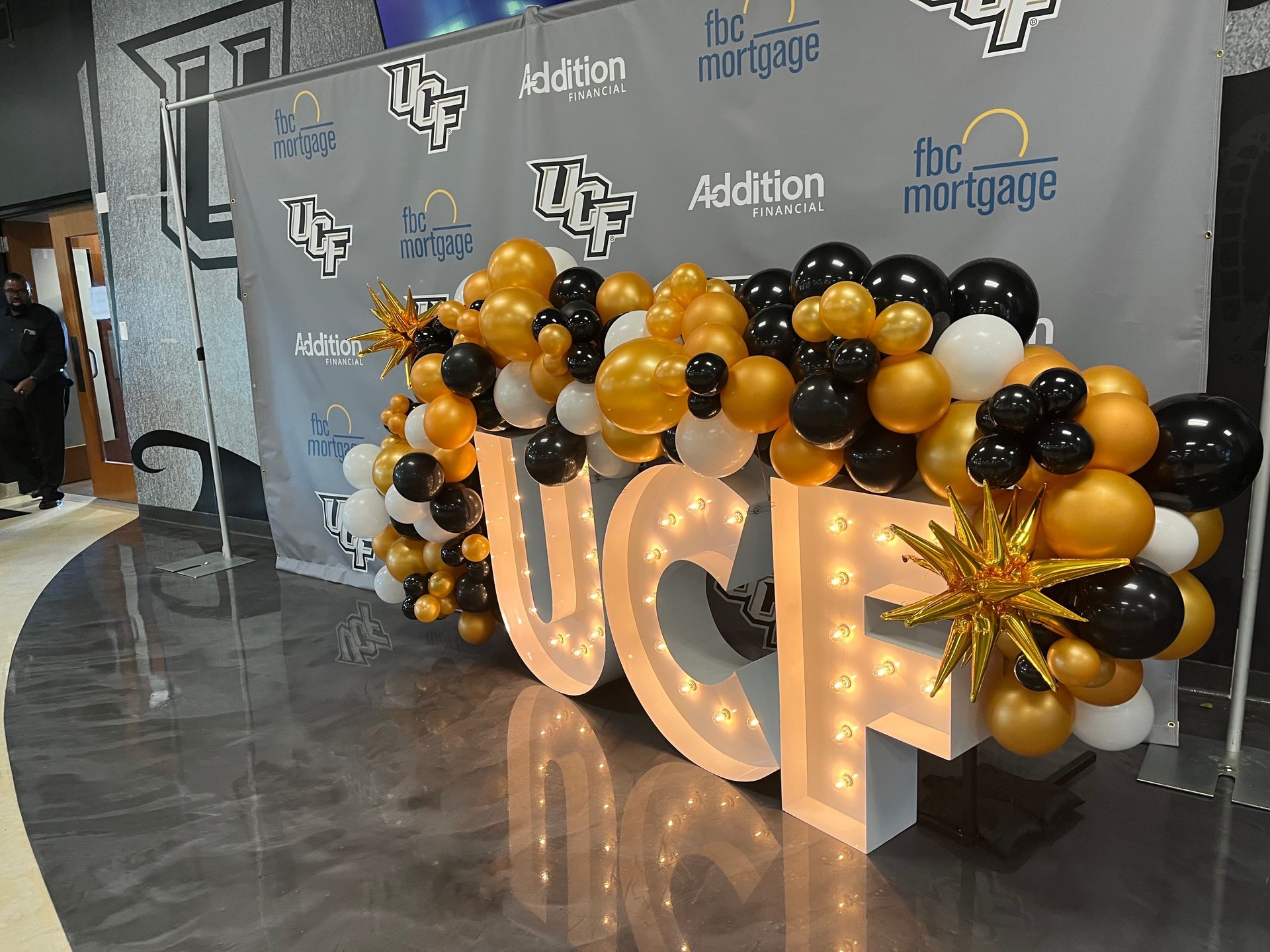 A large sign that says ucf is surrounded by balloons.