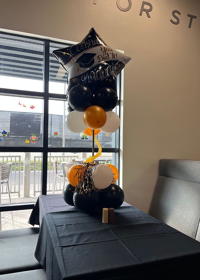 A table with a bunch of balloons on it in front of a window.
