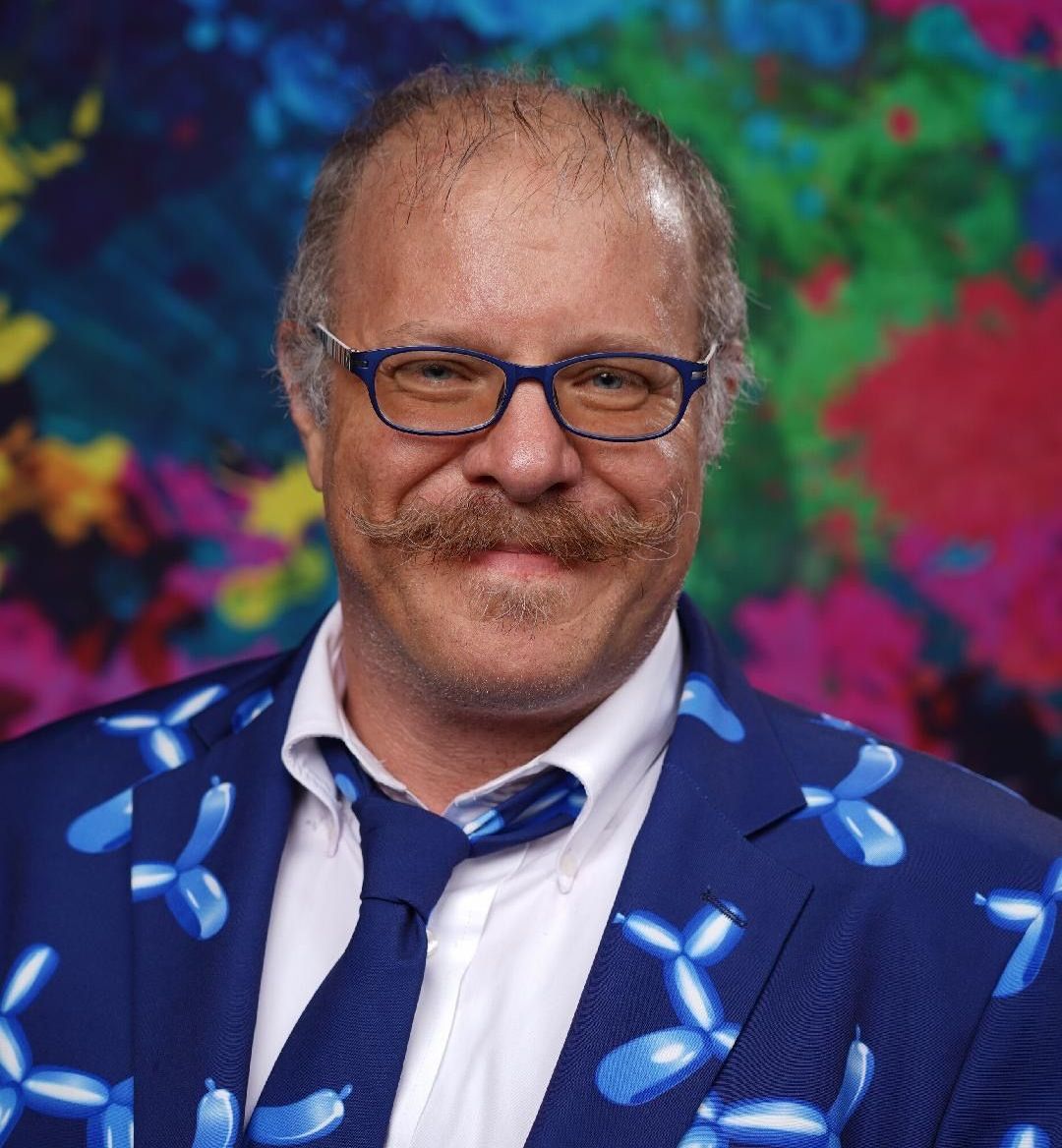 A man wearing a blue suit and tie with balloons on it.