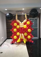A man made out of balloons is lifting a barbell.