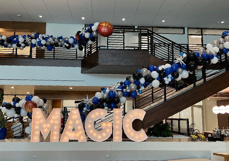 A large sign that says magic is surrounded by balloons.