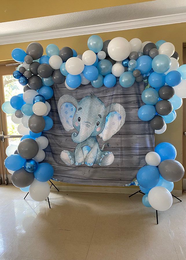 A baby shower backdrop with balloons and a picture of an elephant.
