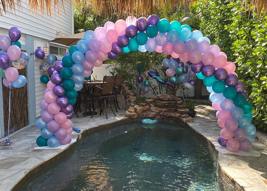 A balloon arch over a pool decorated for a birthday party.