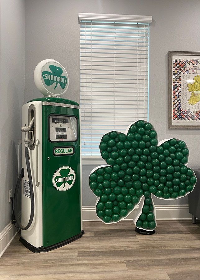 A gas pump and a shamrock made of balloons in a room.