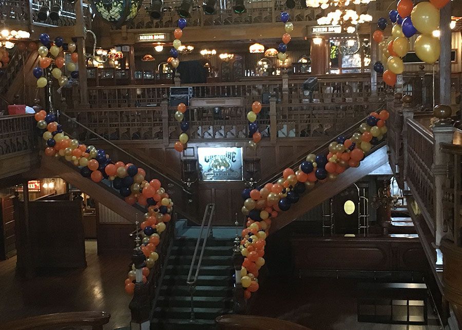 A staircase is decorated with orange and blue balloons