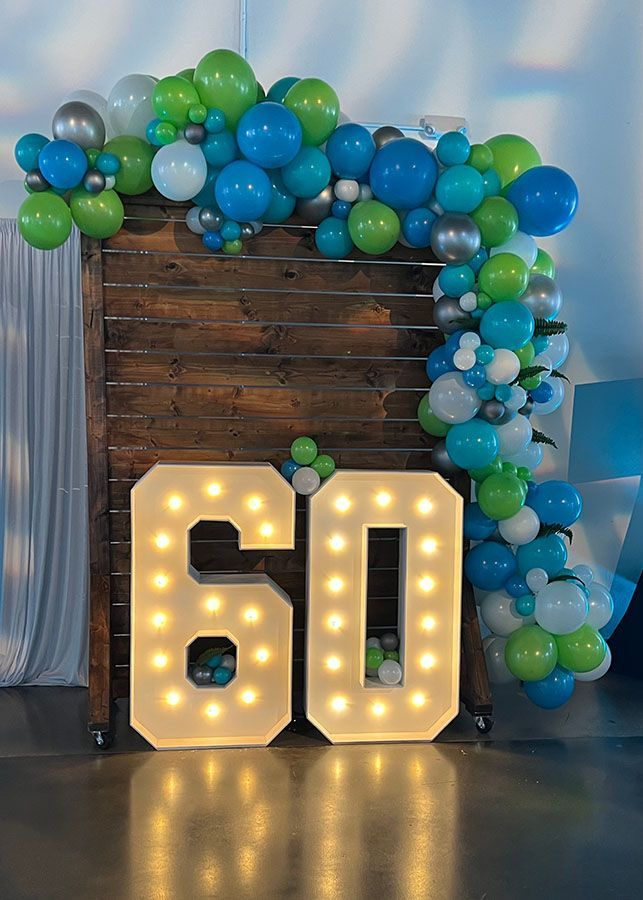 The number 60 is surrounded by blue and green balloons.