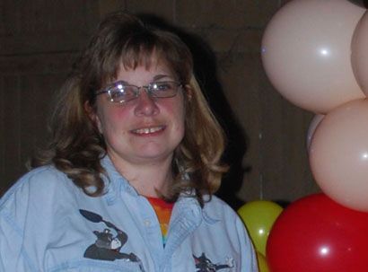 A woman wearing glasses is standing in front of balloons