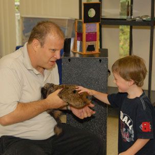 A man is holding a small animal in his hands while a boy looks on.