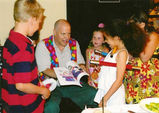 A man is reading a book to a group of children