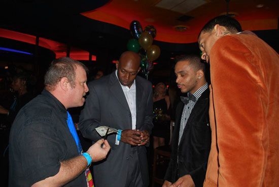 A group of men in suits are standing in a room with balloons on the ceiling.