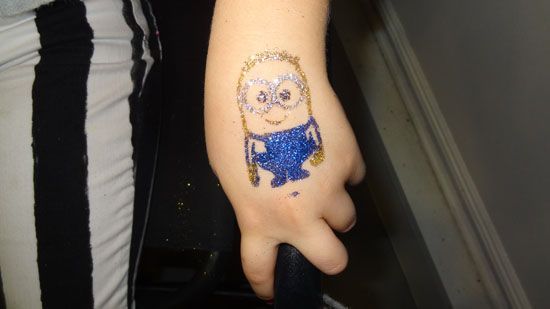 A child has a minion tattoo on their hand.